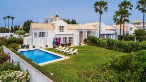 A modern house with a swimming pool, a well-maintained lawn, and palm trees. - Villa Farol OCV - Ocean Front (Galé)
