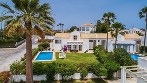 A white villa with a swimming pool, surrounded by palm trees and a well-maintained lawn. - Villa Farol OCV - Ocean Front (Galé)