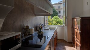 A kitchen with a large window, a toaster, a sink, and wooden cabinets. - The Rediscovered House (Firenze)