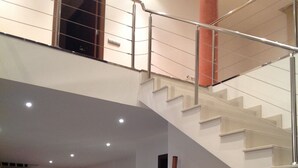 Un amplio espacio habitable con una escalera, una mesa de comedor con sillas y un pequeño armario.