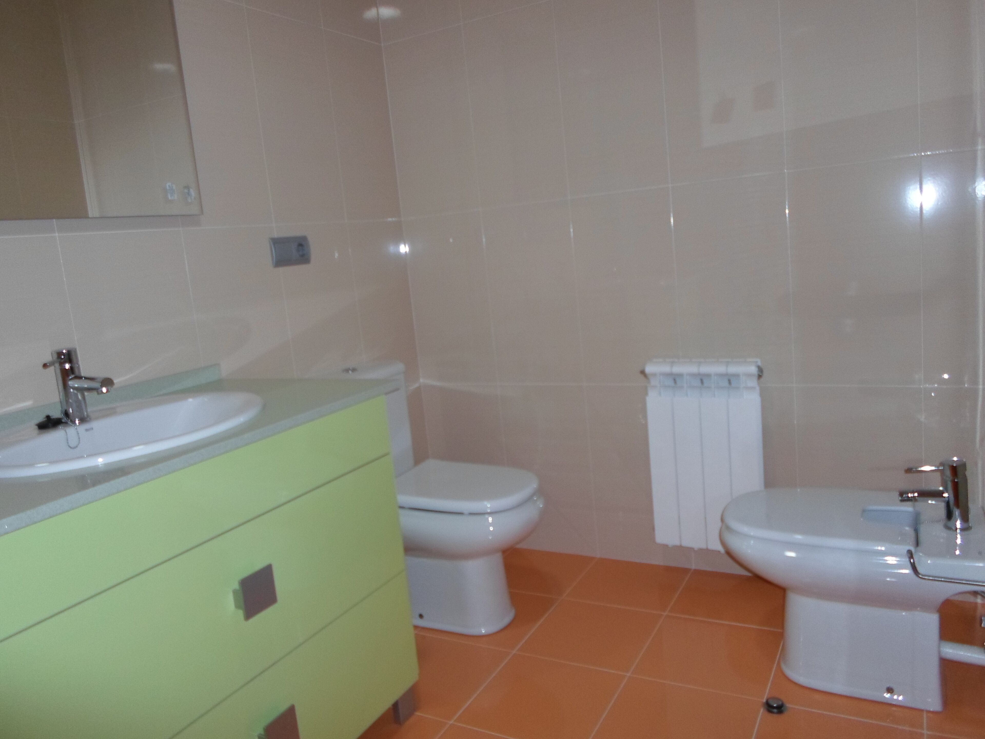 Een badkamer met een wastafel, twee toiletten en een spiegel.