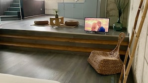 A modern living room with a TV, wicker furniture, and a staircase. - Apartment in Yeste (2 places) (Yeste)
