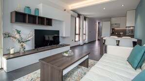 A modern living room with a sofa, coffee table, TV, and kitchen area in the background. - Apartment in Yeste (2 places) (Yeste)