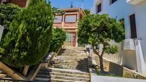 A set of stone steps leading to a building with a colorful gate, surrounded by greenery and modern architecture. - Apartment in Yeste (2 places) (Yeste)