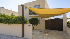 A modern building with a stone-paved entrance, a wooden gate, and a yellow shade sail. - Villa Callista -  Modern Villa that sleeps 8 guests  in 4 bedrooms (Paphos)