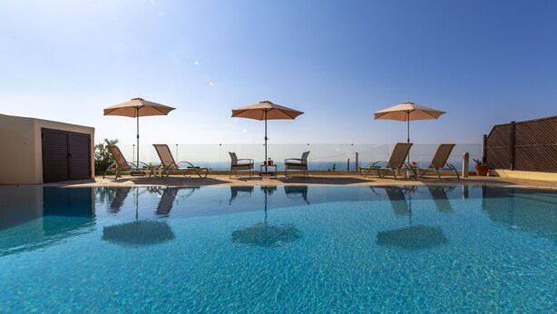 A clear blue pool with lounge chairs and umbrellas, overlooking a scenic view. - Villa Callista -  Modern Villa that sleeps 8 guests  in 4 bedrooms (Paphos)