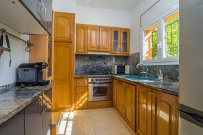 A kitchen with wooden cabinets, a stove, a microwave, and a sink.