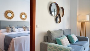 A hotel room with a bed, a sofa, and wall-mounted mirrors. - iloftmalaga Puerta del Mar II (Málaga)