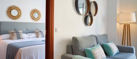 Habitación de hotel con cama, sofá y espejos en la pared.