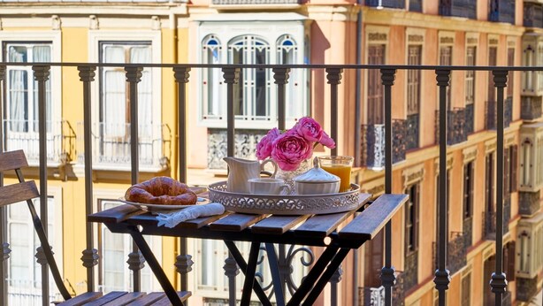 A balcony with a table set with croissants, a pitcher, a vase with flowers, and a glass of orange juice. - iloftmalaga Puerta del Mar II (Málaga)