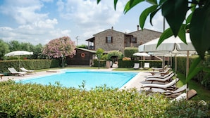 A swimming pool with lounge chairs, a stone house, and a well-maintained garden. - 8 RIBOCCHI HOLIDAY HOME: THREE-ROOM APARTMENT WITH POOL SEA, THERMAL BATHS AND VILLAGES  (Campiglia Marittima)