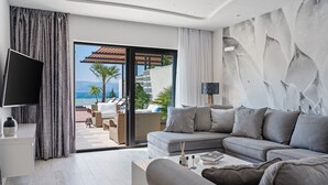 A modern living room with a grey sofa, a flat-screen TV, and a view of the outdoors.