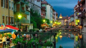 A canal-side street with buildings, a bridge, and a restaurant with outdoor seating. - Waterfront apartment in the historic district with a large terrace. (Annecy)