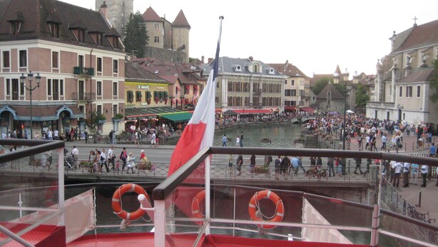 A balcony with red flooring, a flag, and lifebuoys.