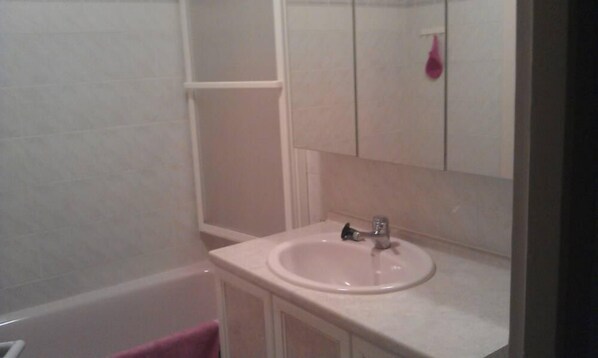 Ein Badezimmer mit einem weißen Waschbecken, einem Spiegel und einer Badewanne.
