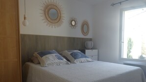 Una camera da letto con un letto, un comodino, una cassettiera e una finestra che si affaccia sul verde.