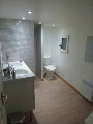 Ein Badezimmer mit einem Doppelwaschbecken, einer Toilette und einer Duschkabine.
