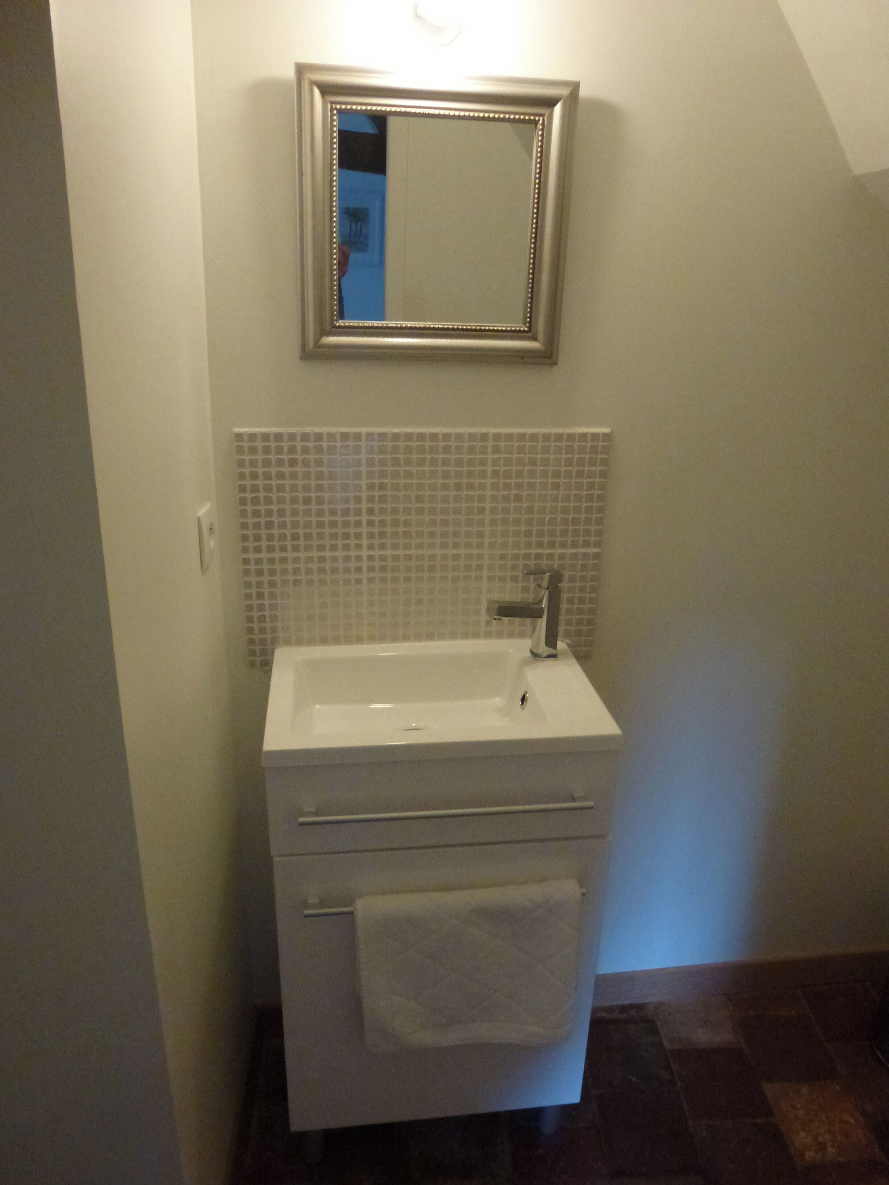 A bathroom with a white sink, a mirror, and a tiled backsplash.