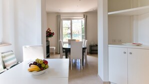 A modern kitchen with white cabinetry, a dining area with a table and chairs, and a fruit bowl on the table. - Villa Il Rifugio, villa with private pool (Pietrasanta)