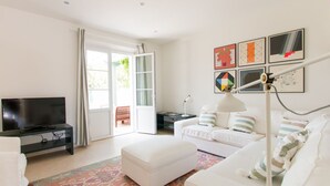 A modern living room with a flat-screen TV, a white sofa, a coffee table, and a patterned rug. - Villa Il Rifugio, villa with private pool (Pietrasanta)