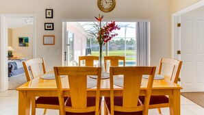 A dining area with a wooden table and chairs, a vase with flowers, and a clock on the wall. - Town Center Reserve - Superior Disney Villa with Lake View, free WiFI & Netflix (Davenport)
