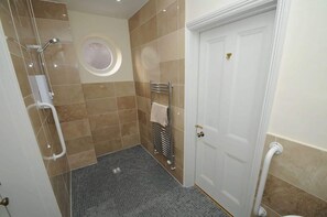 Ein Badezimmer mit Dusche, Handtuchhalter, Tür und kleinem Fenster.