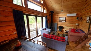 Interior de una cabaña con una mesa de comedor, sofá y chimenea.