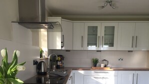 Une cuisine moderne avec des armoires blanches, une hotte de cuisinière en acier inoxydable et un sol carrelé à motifs hexagonaux.