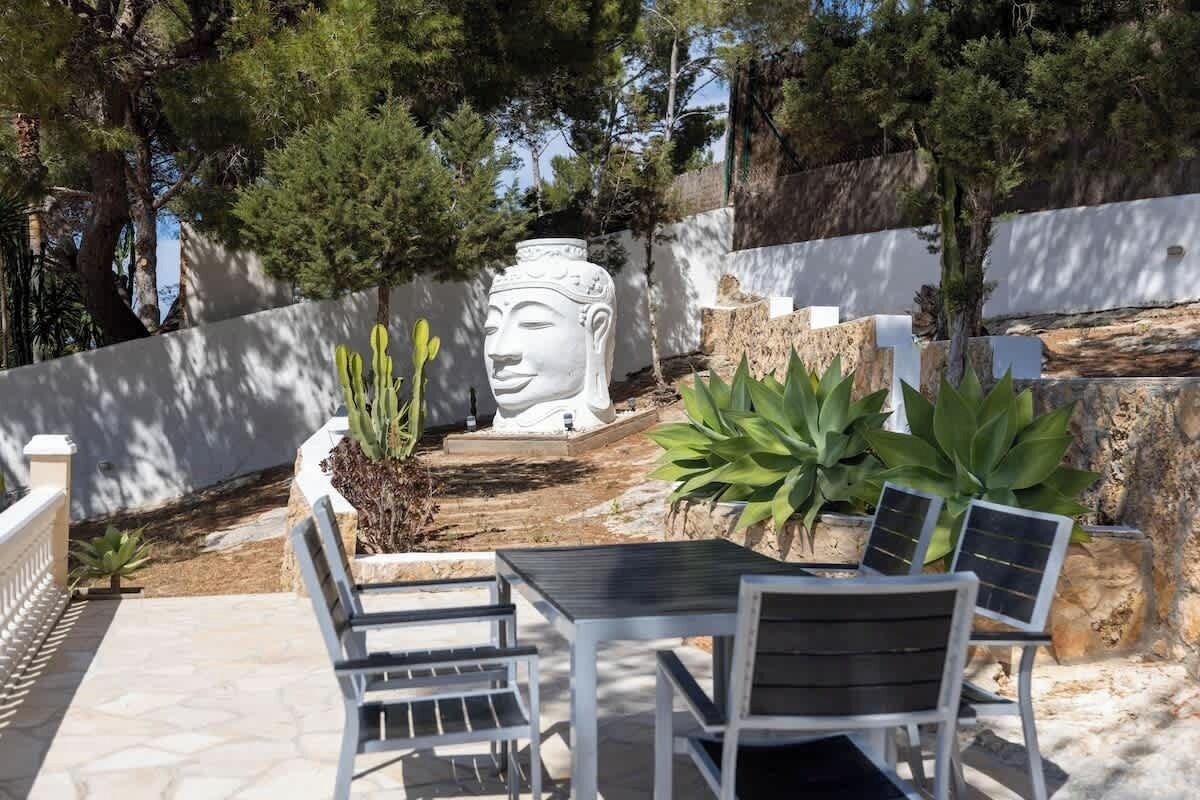 An outdoor seating area with a Buddha statue, cacti, and solar-powered lights.
