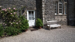 A stone building with a white door, a bench, and potted plants.