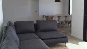 A modern living room with a sectional sofa, a dining table with chairs, and a small white table. - 4 Beds & 4 Bath, 150mts from the beach, Private Heated Pool, BBQ (Fuengirola)