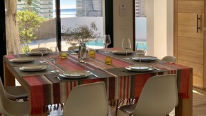 A dining area with a table set for four, a view of the sea, and a wooden door. - 4 Beds & 4 Bath, 150mts from the beach, Private Heated Pool, BBQ (Fuengirola)