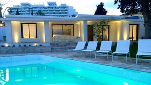 A modern pool area with a clear pool, white lounge chairs, and a building with large windows and steps leading to a door. - 4 Beds & 4 Bath, 150mts from the beach, Private Heated Pool, BBQ (Fuengirola)