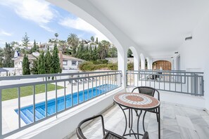 Un balcon avec une piscine, un espace salon extérieur et une vue sur un quartier résidentiel.