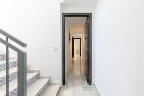 Un pasillo con una escalera a la izquierda y una puerta que da a otra habitación a la derecha.