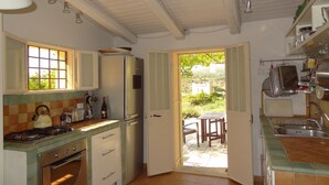 A kitchen with a stove, oven, refrigerator, and a dining area with a table and chairs.