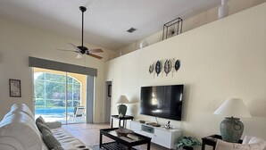 A modern living room with a white sofa, a coffee table, a TV, and a ceiling fan. - Executive Villa with lake views,  south facing pool 4 bed 3 bath. Games room (Davenport)
