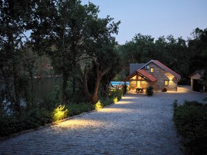 Une maison en pierre avec un toit rouge, une allée pavée et une vue sur un lac.