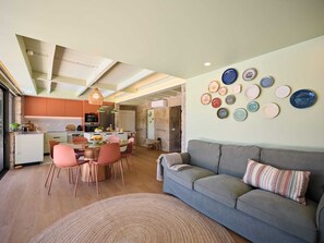 Una cocina moderna con comedor, un sofá gris y una pared decorada con platos.