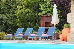 A poolside area with lounge chairs and a barbecue grill. - Private Riverside Hideaway | Infinity Pool & Kayak (Maureles)