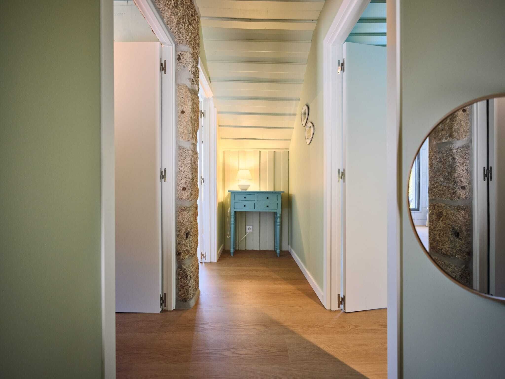 A hallway with wooden flooring, white doors, and a blue cabinet with a lamp.