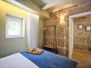 A bedroom with a bed, a tray of breakfast, a window, a stone wall, and a door. - Private Riverside Hideaway | Infinity Pool & Kayak (Maureles)