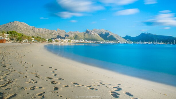 A beach with footprints leading to the water, a clear sky, and mountains in the background. - Family villa with private pool, 500 m from the beach (Alcúdia)