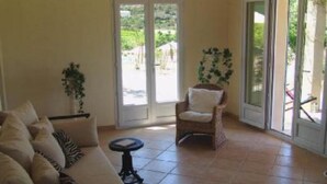 A living room with a sofa, a chair, a small table, and a sliding glass door leading to an outdoor area. - House / Villa - Coustouge (Coustouge)