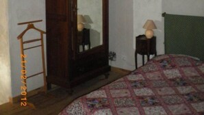Un dormitorio con techo de madera, un espejo grande, una cama con colcha estampada y una mesita de noche con lámpara.