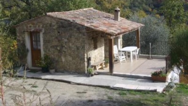Una casa de piedra rústica con un pequeño patio y mobiliario exterior.