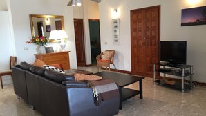 Un salon avec un canapé, un téléviseur et un ventilateur de plafond.