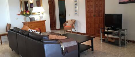 Ein Wohnzimmer mit einer Couch, einem Fernseher und einem Deckenventilator.