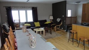Un salon moderne comprenant un canapé, des fauteuils, une table à manger et un coin cuisine.