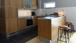 Une cuisine moderne avec des meubles en bois, un four encastré, un évier et des tabourets de bar.